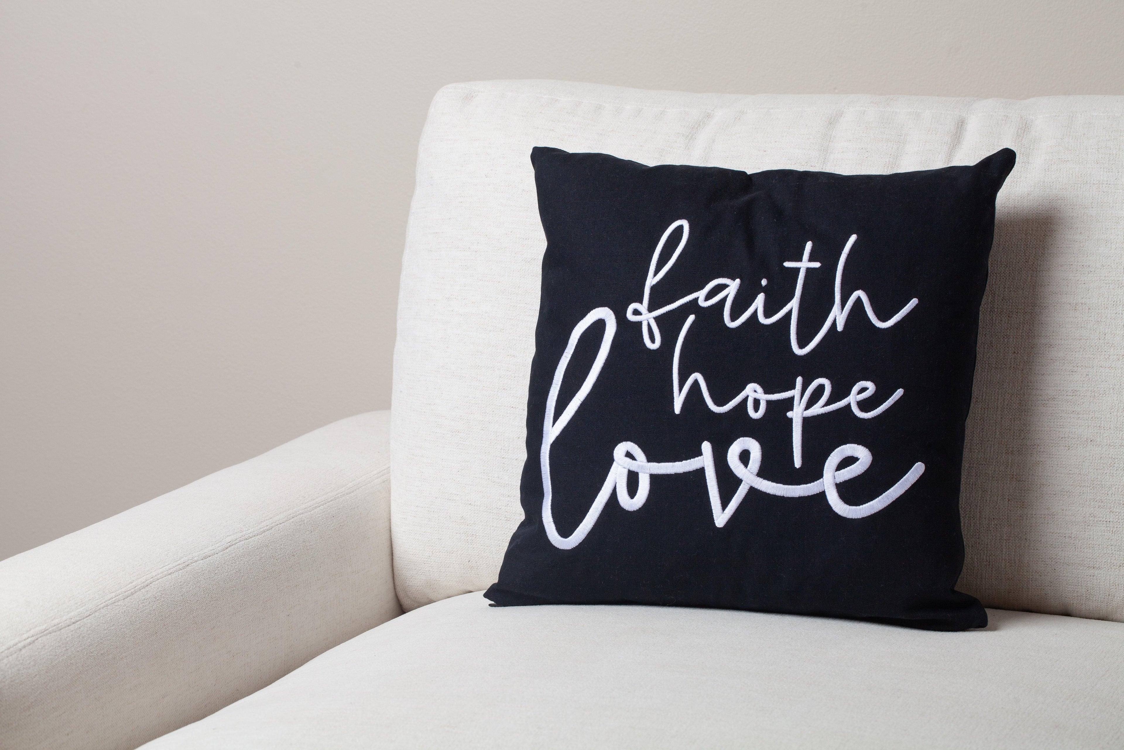 Black Faith Hope Love embroidered pillow styled on white modern sofa – 1 Corinthians 13:13 scripture adds faith and elegance to Christian living room