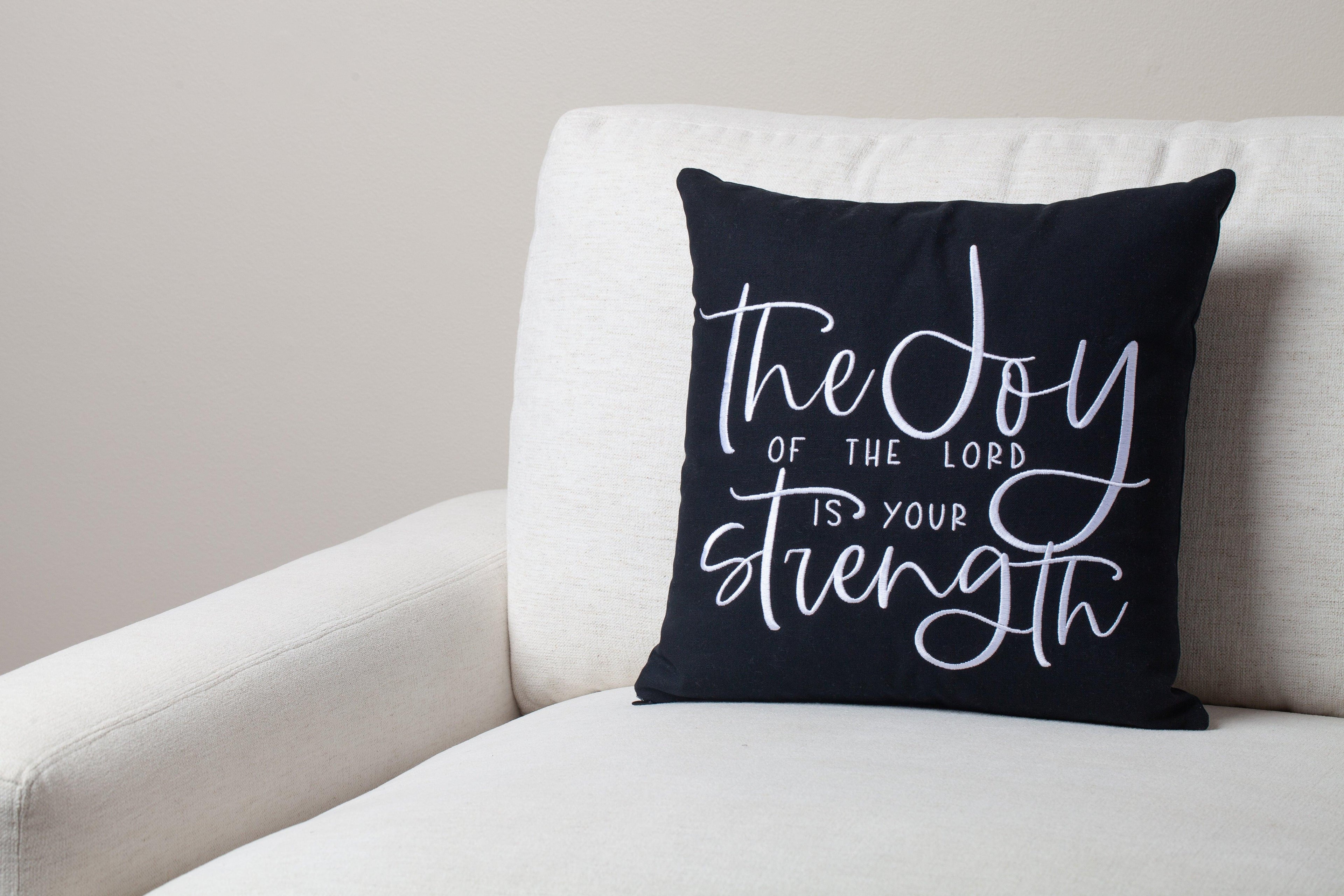 Black Joy & Strength embroidered pillow on white modern sofa – Nehemiah 8:10 'joy of the Lord is your strength' inspires Christian living room