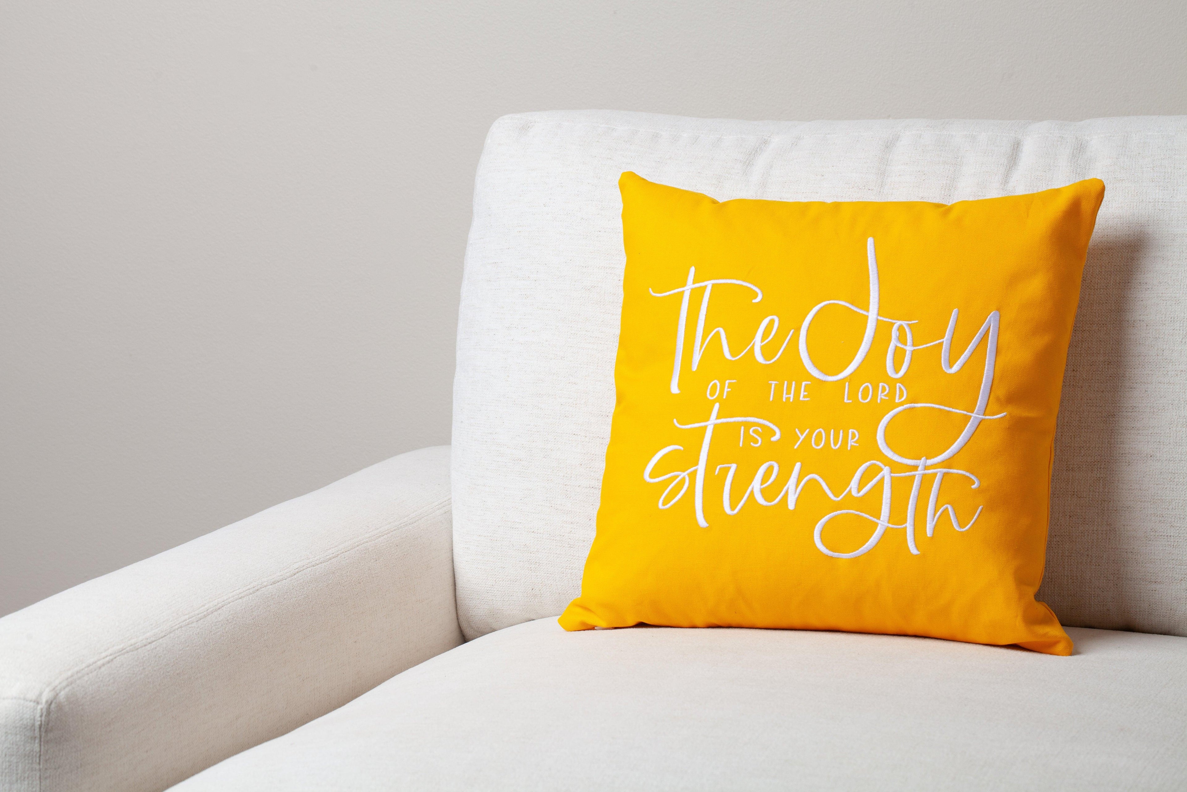 Yellow Joy & Strength pillow on white cozy sofa – bright Nehemiah 8:10 'joy of the Lord is your strength' adds encouragement to warm Christian setting